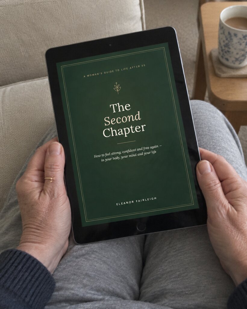 Hands holding an iPad showing the cover of The Second Chapter, a mug of tea beside the sofa